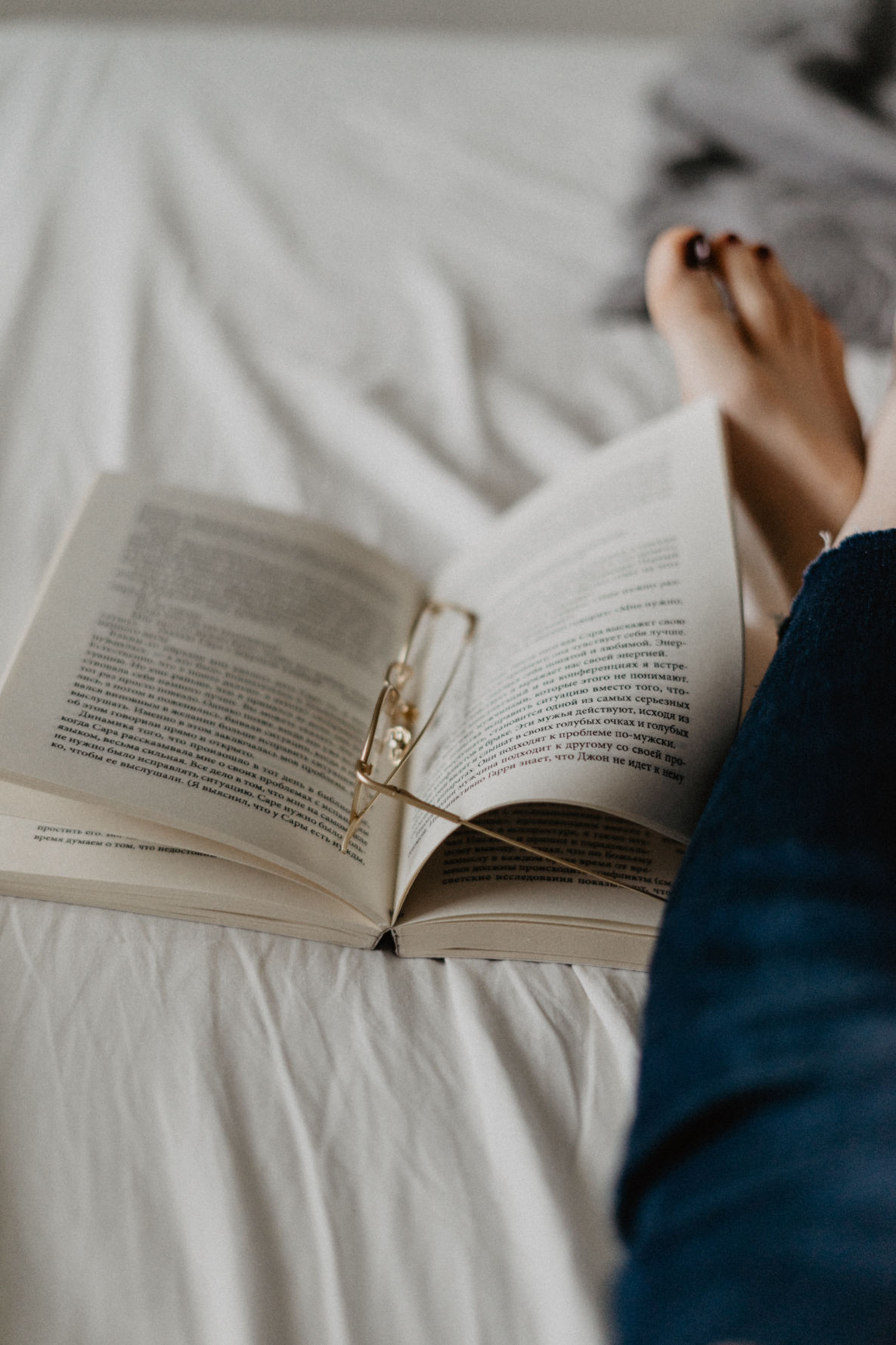 Book on a bed with reading glasses