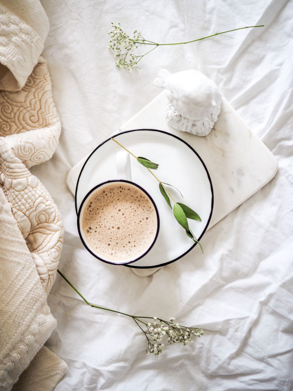 Fresh coffee on plate on bed