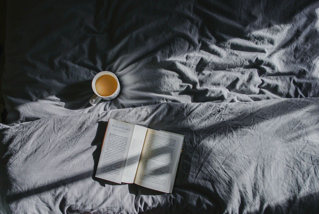 coffee cup and book on a bed